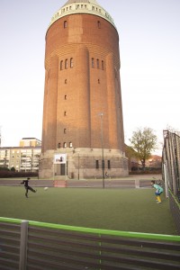 Två pojkar spelar fotboll på den nya multiarenan med Södervärnstornet i bakgrunden.