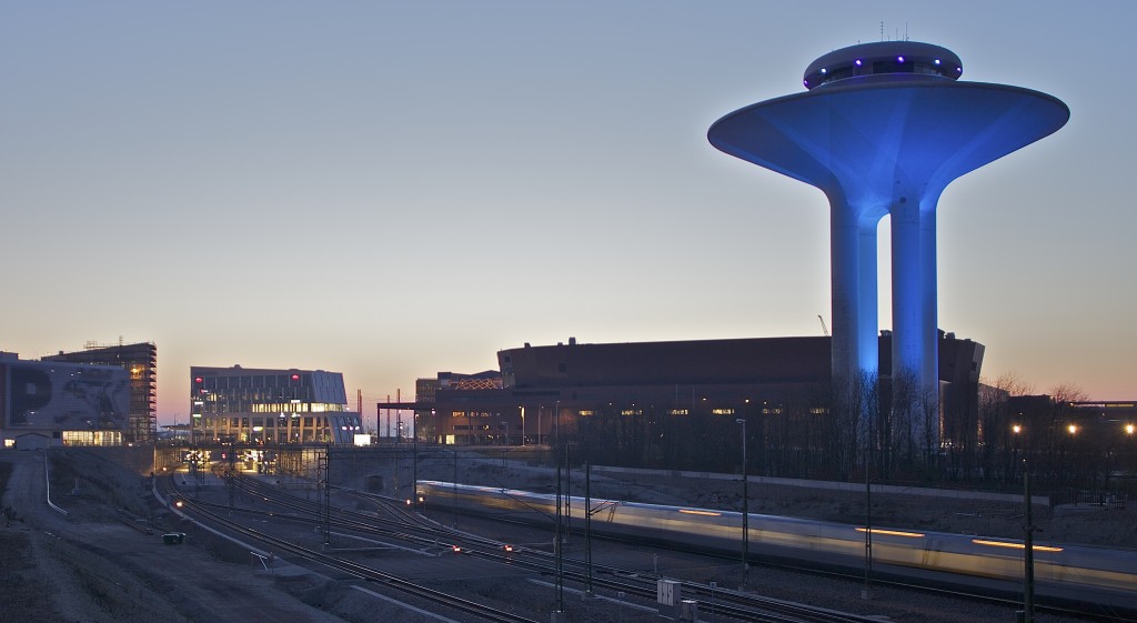 Ett tåg kör in till Hyllie station riktning Köpenhamn. Malmö Arena och Vattentornet syns i bakgrunden.