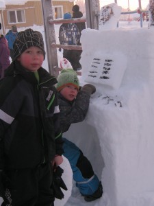 Två pojkar vid en snöskulptur i form av ett piano
