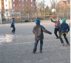 Fyra pojkar som spelar fotboll på en grusplan