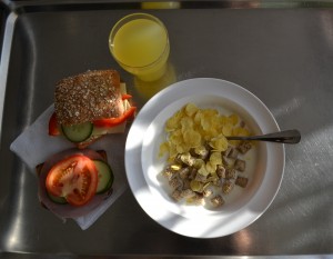 Frukostbricka med fil, flingor, smörgåsar och apelsinjuice