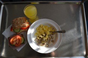 Frukostbricka med fil, flingor, smörgåsar och apelsinjuice